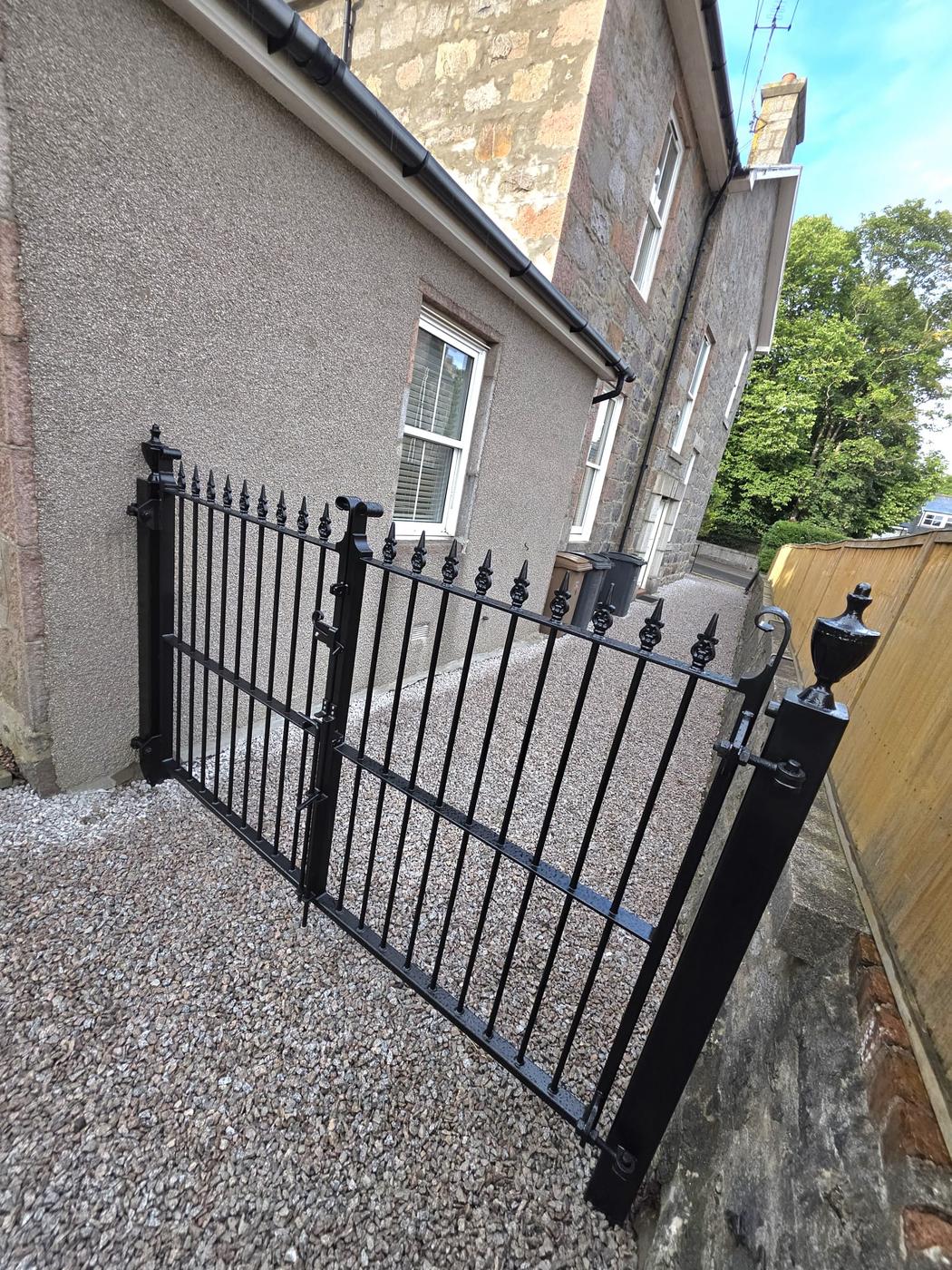 Black wrought iron double gates with spear-top railheads, fitted at a granite house driveway in Aberdeen